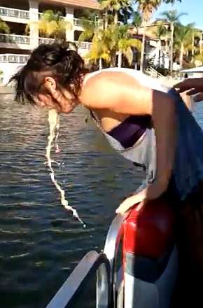 Girl heaves over side of boat vomit